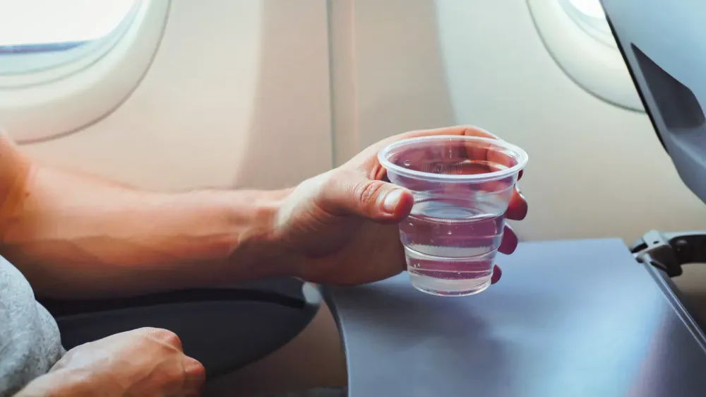 Passenger drinking water in airplane during flight.